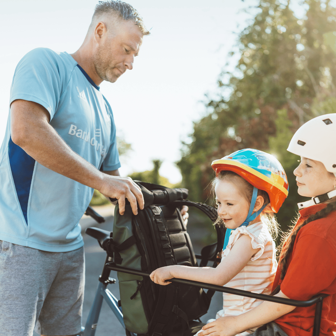 Parent fitting a child's helmet beside the Kuma Alpa cargo bike