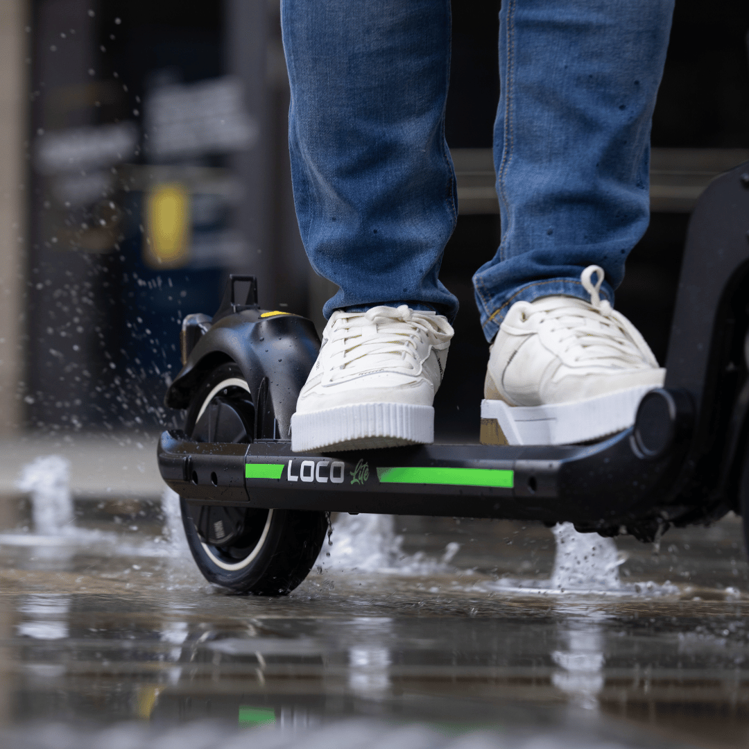 Rider standing on LOCO Lite electric scooter in the rain