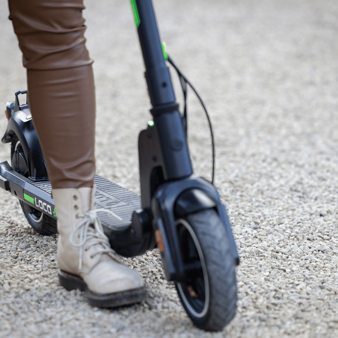 Person riding the LOCO Lite electric scooter on gravel path