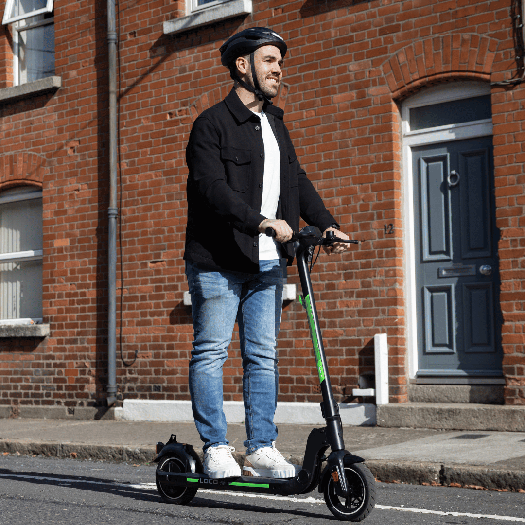 Man commuting on the LOCO Lite electric scooter outside brick buildings