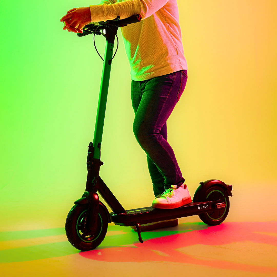 Rider using the LOCO City electric scooter in a colourful studio setting