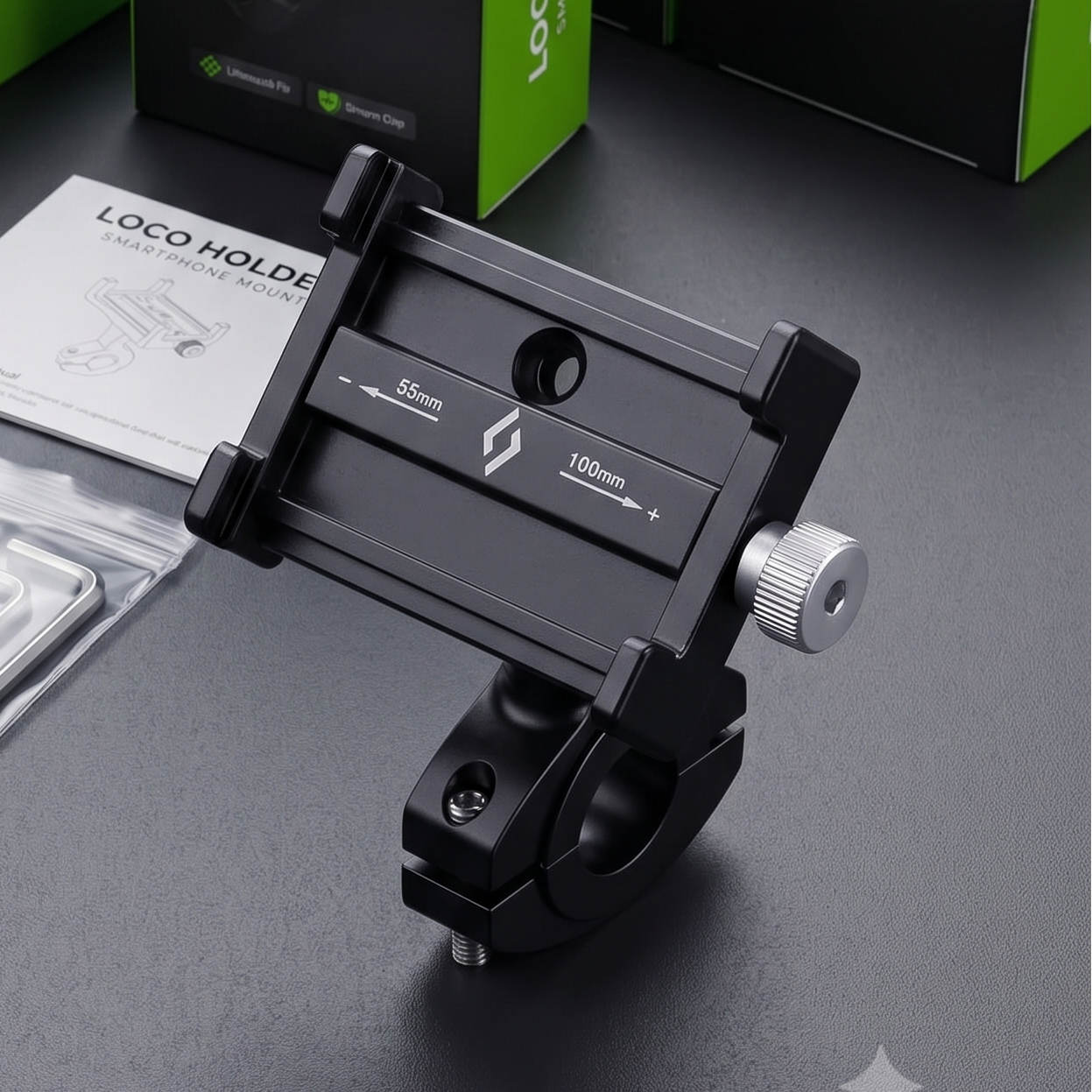 A black LOCO Holder smartphone mount with silver hardware and a silver instruction booklet, displayed in front of its green and black retail packaging boxes on a dark grey surface.